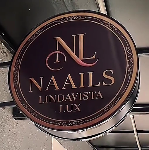 Placa redonda del salón con el monograma NL y las letras Naails Lindavista Lux en dorado sobre ciruela