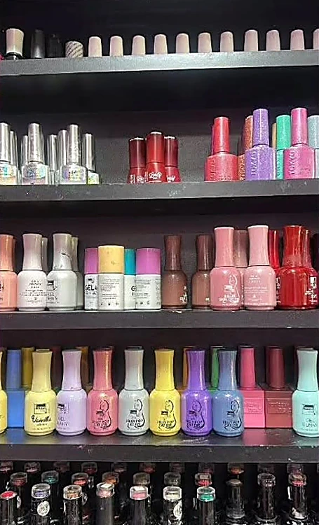 Repisa negra con frascos de gel ordenados por color: rojos, rosas, lilas, amarillos y menta