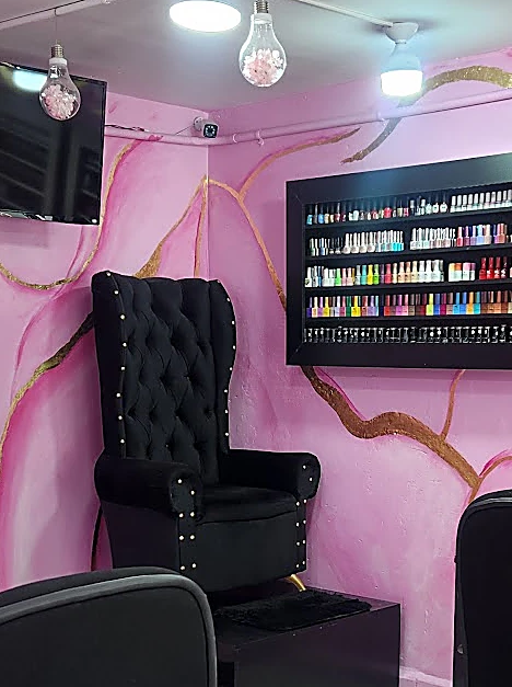 Interior del salón: muro rosa con vetas doradas, sillón negro capitoné y repisa negra con esmaltes de colores