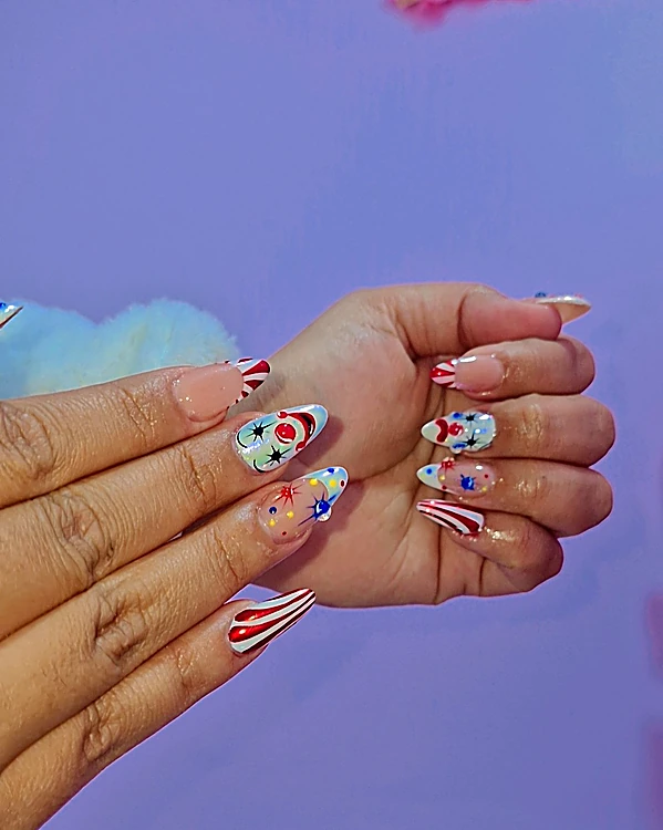 Uñas con bastones rojos y blancos, flores y estrellas sobre fondo lila