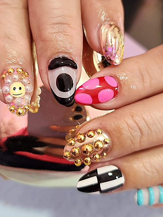 Uñas con charms: carita sonriente, perlas, estoperoles dorados, cuadros blanco y negro y lunares rosas