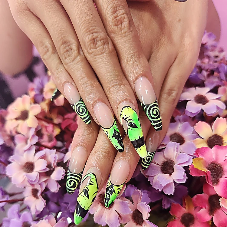 Uñas largas con espirales verde neón y negro sobre fondo de flores lilas